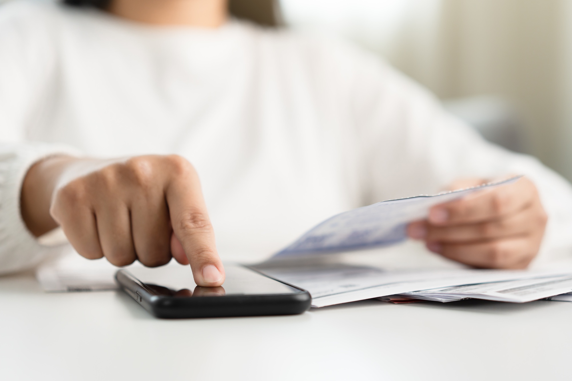Woman holding paper bill invoice and mobile phone
